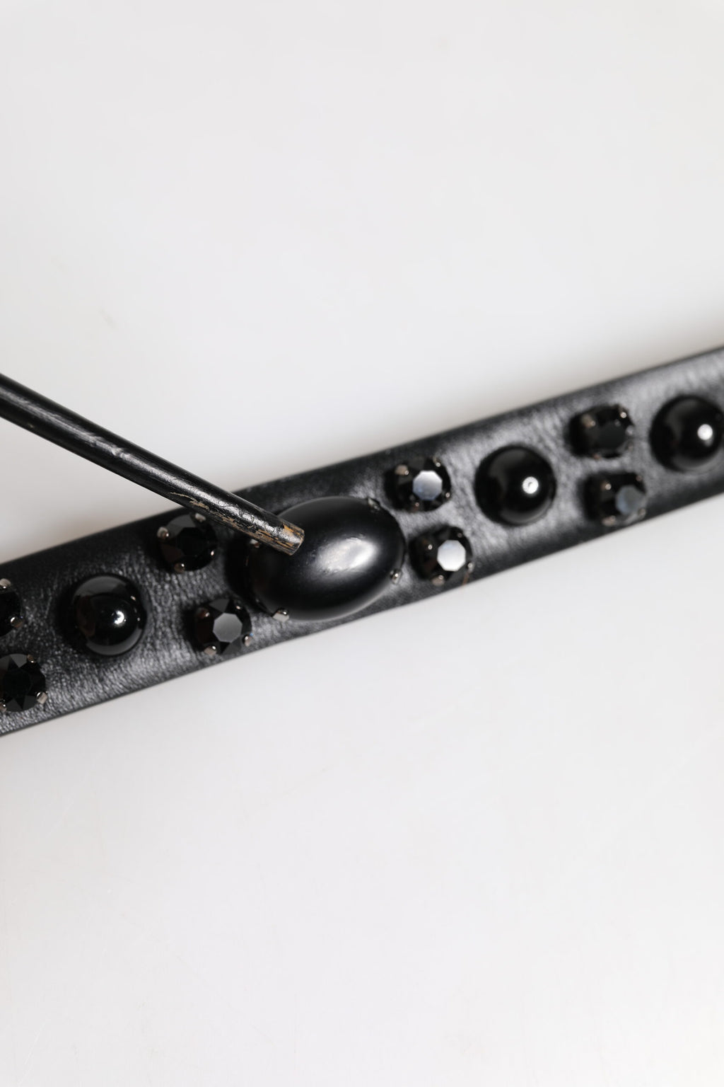 Schwarzer Ledergürtel mit Metall-Logoschnalle und Nieten
